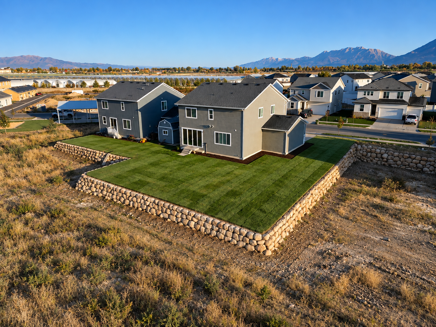 Aerial view of a completed residential landscape with lawn and stone retaining walls